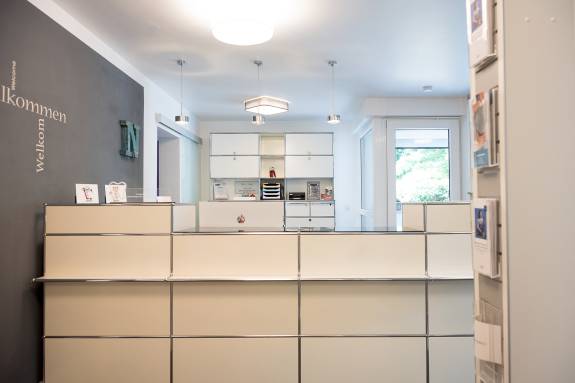 Moderne, helle Empfangstheke in einer Zahnarztpraxis mit minimalistischer Einrichtung.