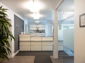 Moderne, helle Empfangstheke in einer Zahnarztpraxis mit minimalistischer Einrichtung.