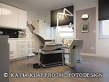 Moderner Behandlungsraum in einer Zahnarztpraxis mit einem ergonomischen Behandlungsstuhl, Deckenlampe und zahnmedizinischen Geräten.